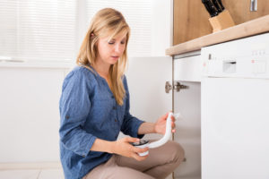 Woman inspects broken drain pipe for damage