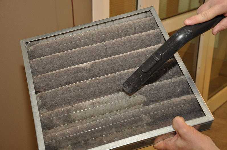 Man using a vacuum to clean air duct cover