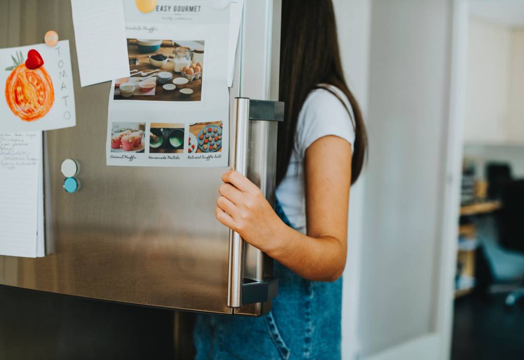 Woman looking in refrigerator deciding how to clean the coils